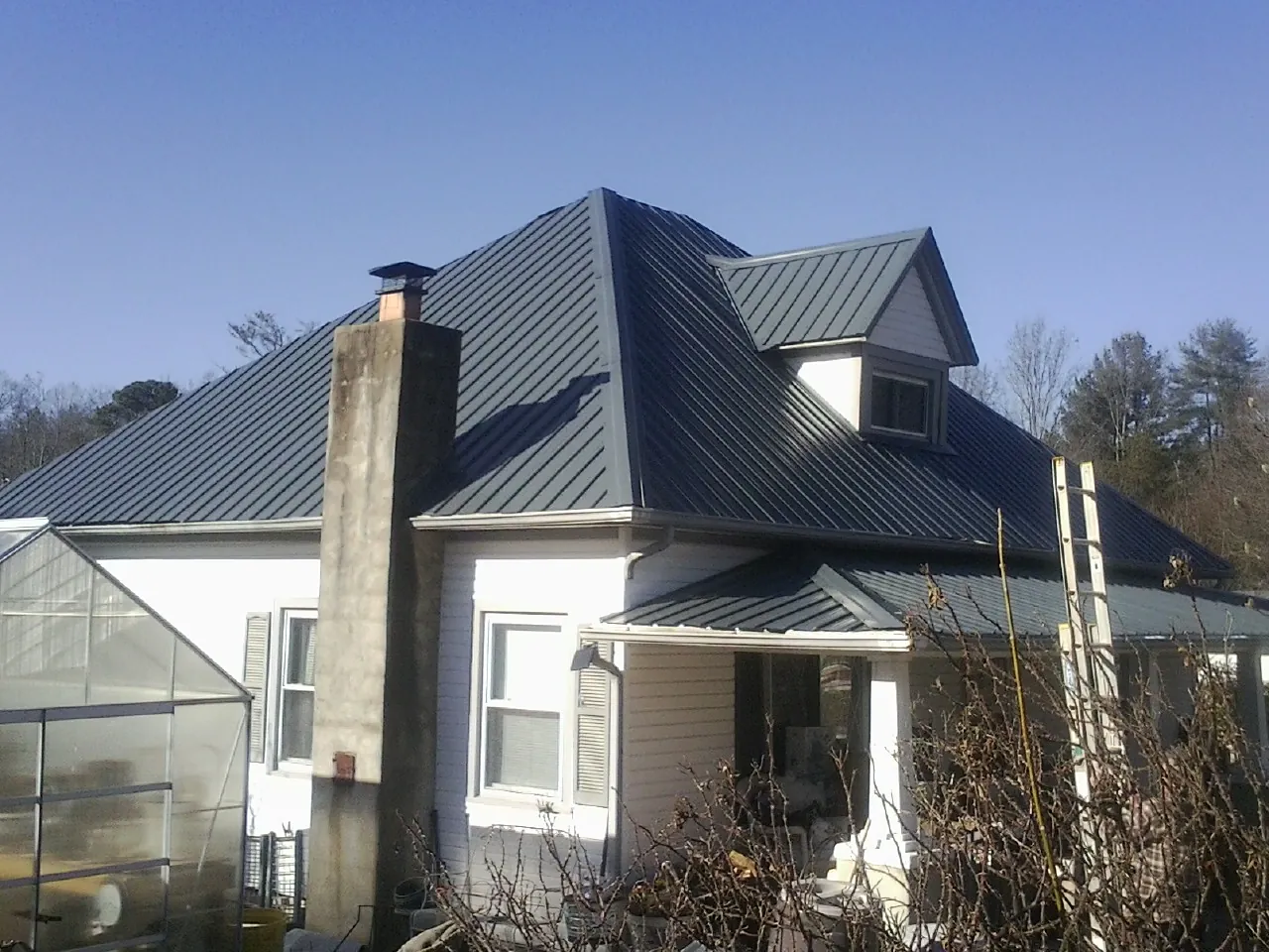 Dark blue standing seam metal roof on a white farmhouse with dormer — Slate & Tile Roof Repair by Roofing Brothers in Cannon Beach