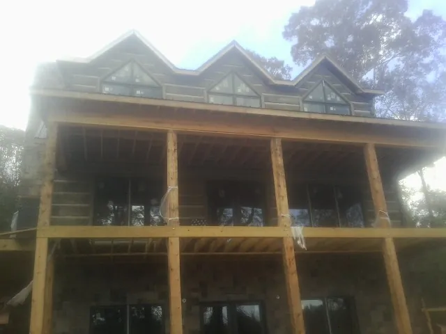 Dormers and porch framing on a large log home under construction — Roof Coating work by our crew in Cannon Beach