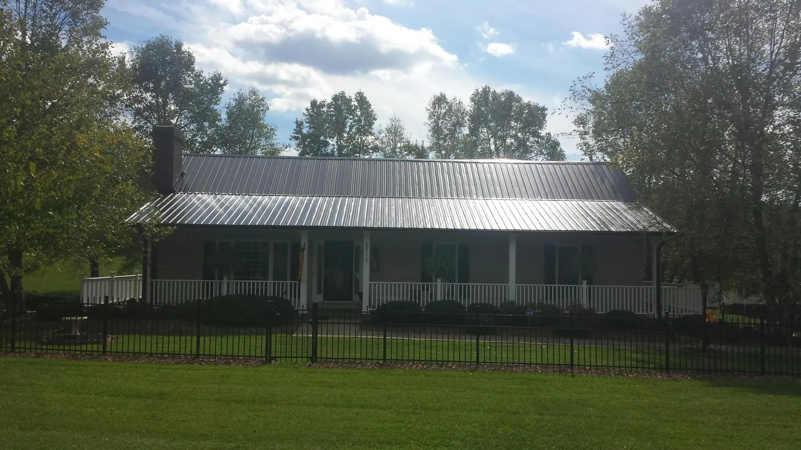 Gray metal roof on a brick ranch with a full width front porch — Gutter Guard Installation work by our crew in Cannon Beach