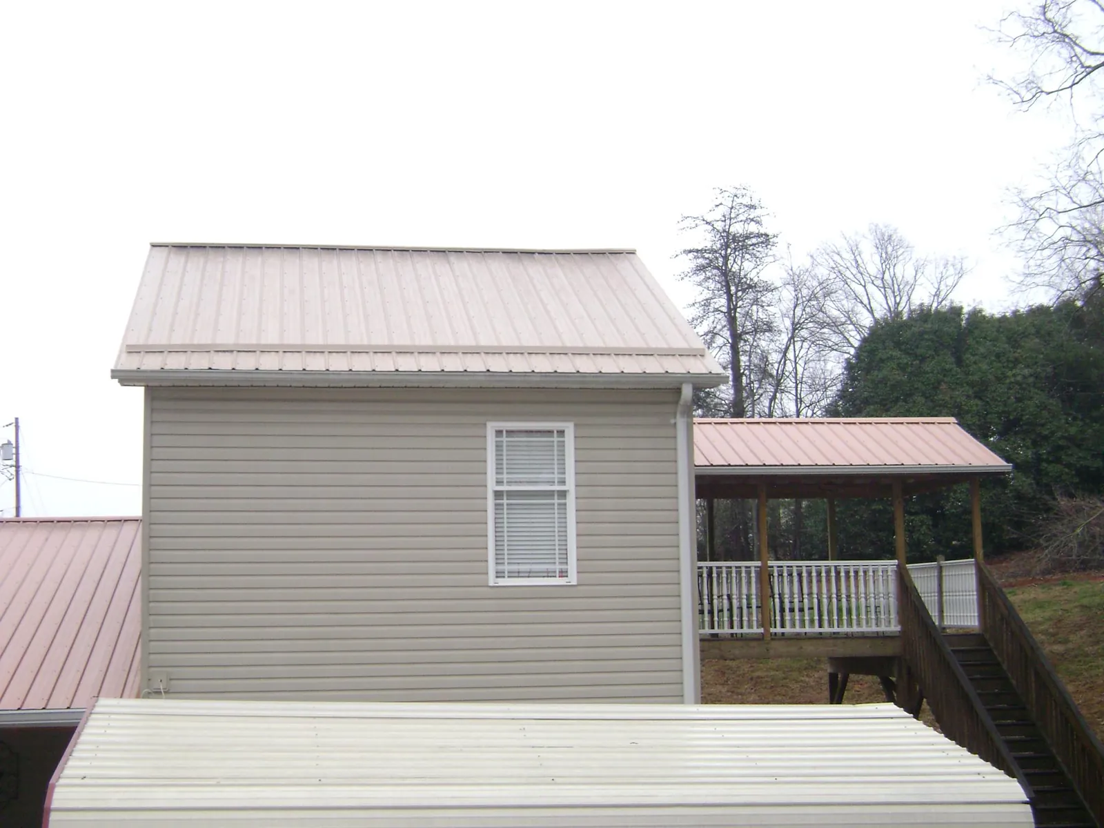 Tan metal roofs on a two story addition and attached porch, from a Roof Replacement job in Cannon Beach